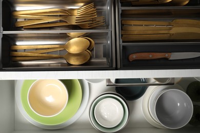 Ceramic dishware and cutlery in drawers indoors, top view