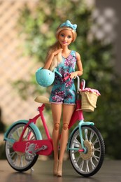Photo of Mykolaiv, Ukraine - September 4, 2023: Beautiful Barbie doll with helmet and bicycle on blurred background