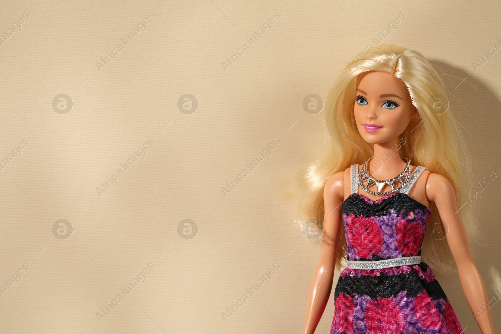 Photo of Mykolaiv, Ukraine - September 4, 2023: Beautiful Barbie doll wearing necklace on beige background, space for text