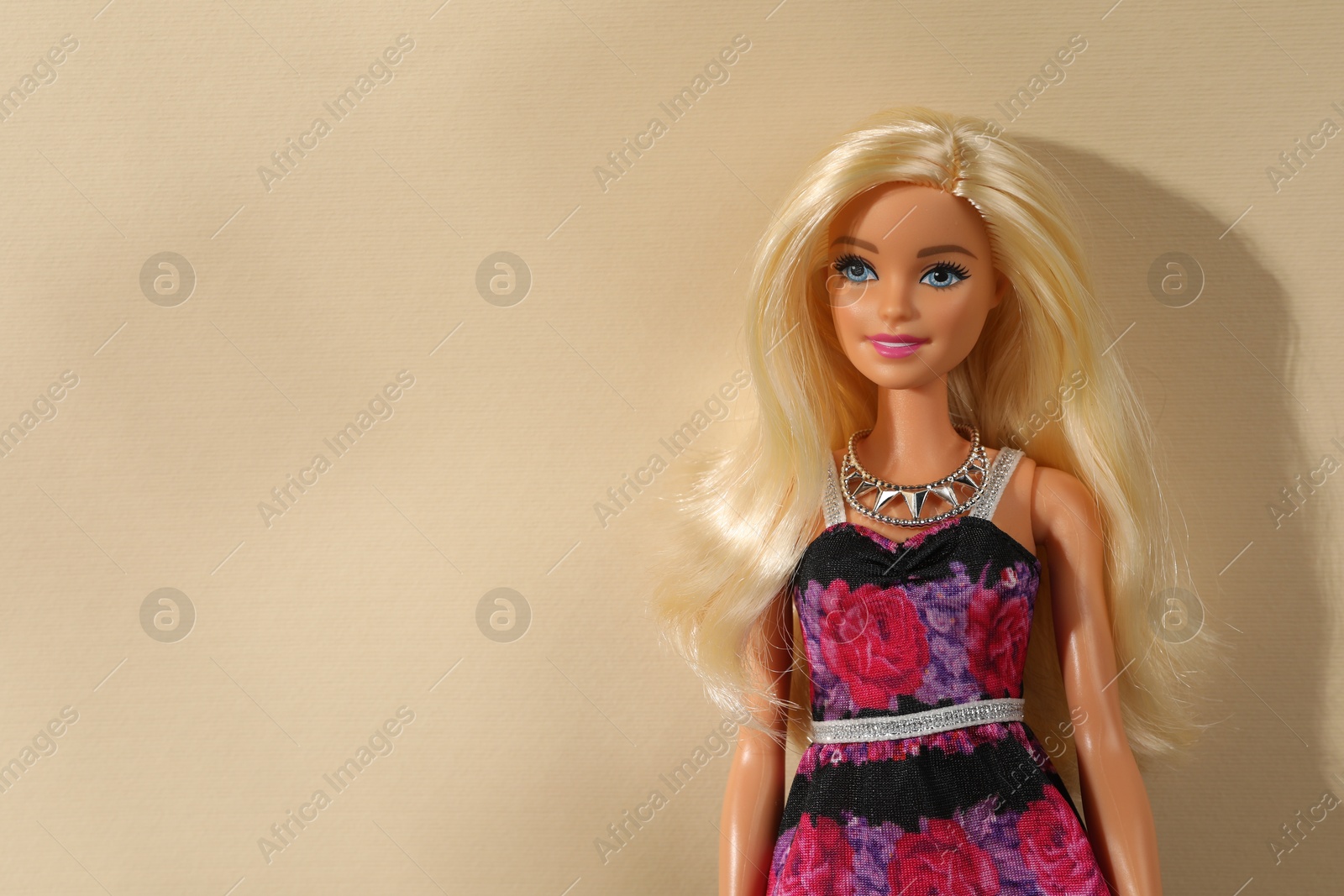 Photo of Mykolaiv, Ukraine - September 4, 2023: Beautiful Barbie doll wearing necklace on beige background, space for text