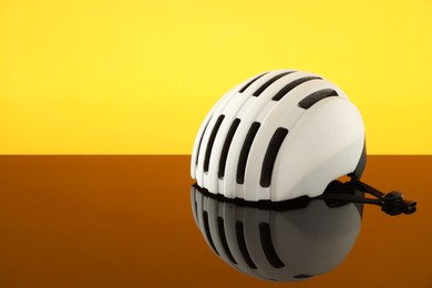 Photo of White protective helmet on mirror surface against yellow background. Space for text