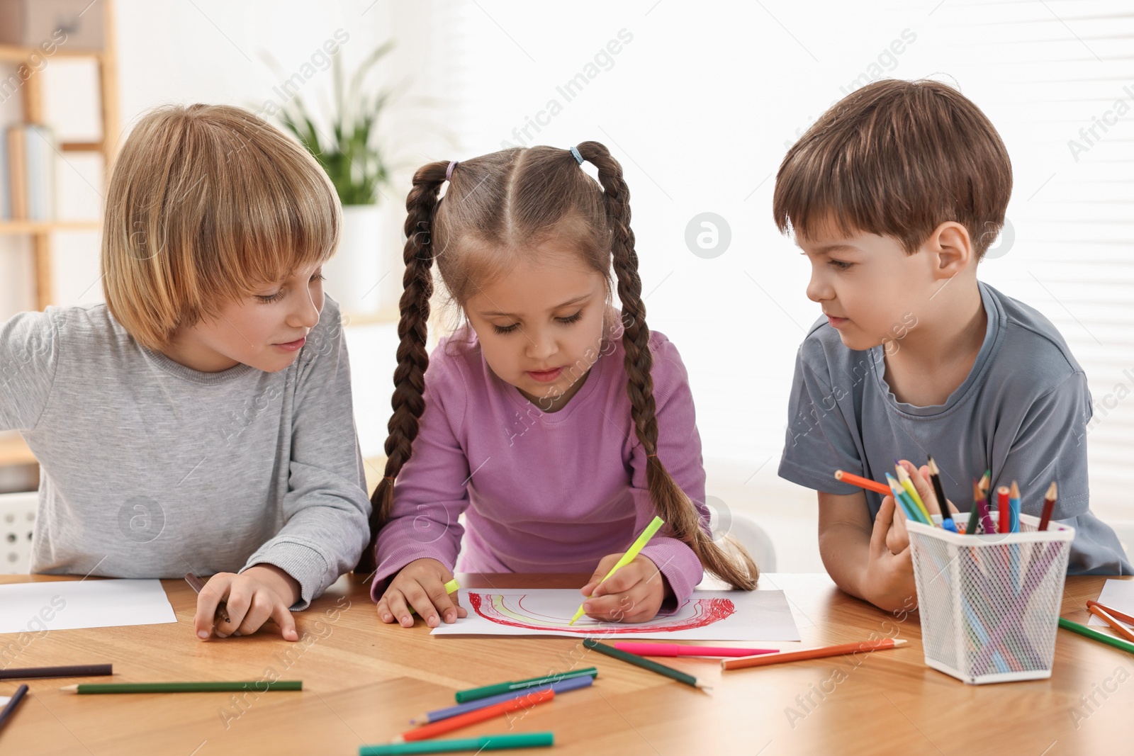 Photo of Cute little children drawing at wooden table indoors