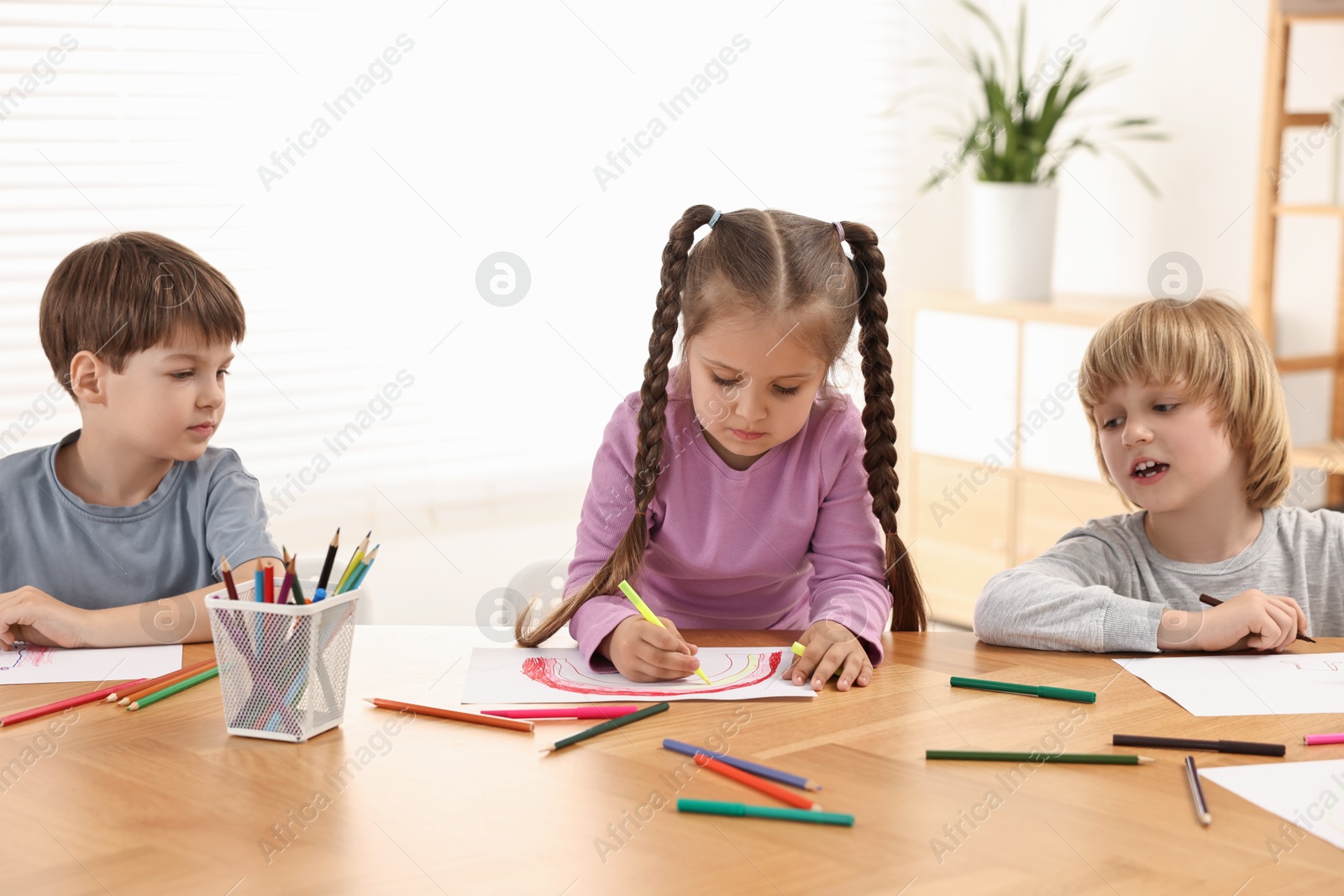 Photo of Cute little children drawing at wooden table indoors