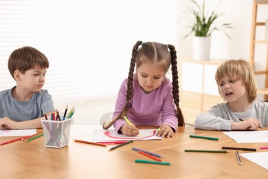 Cute little children drawing at wooden table indoors