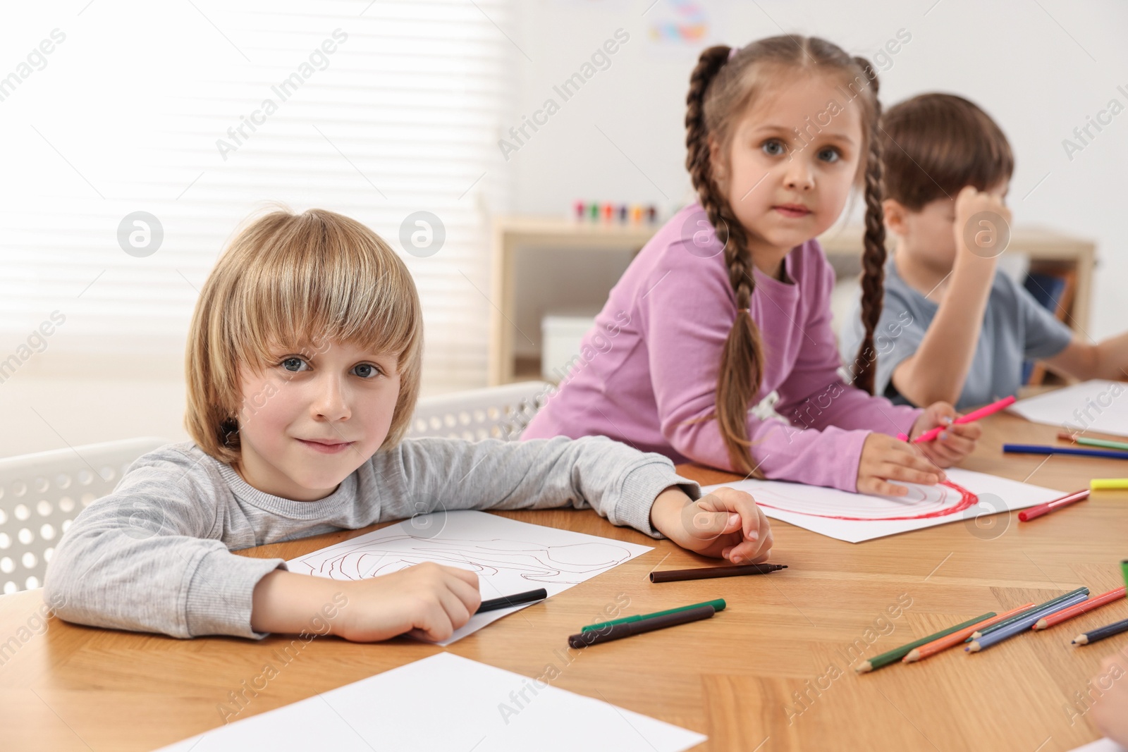 Photo of Cute little children drawing at wooden table indoors