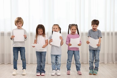 Photo of Group of children with sheets of paper singing indoors