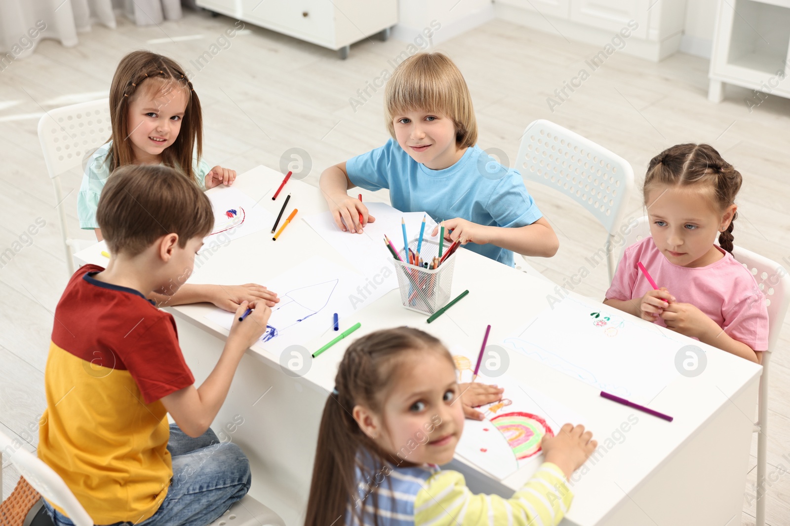 Photo of Group of children drawing at table indoors