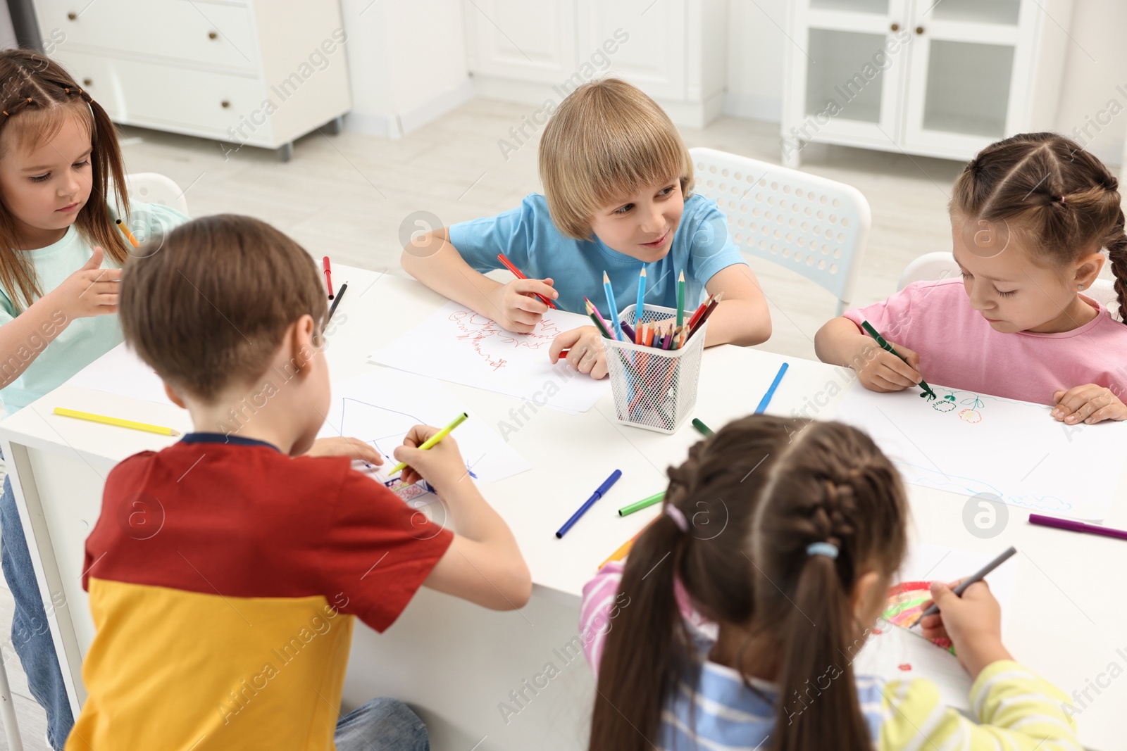 Photo of Group of children drawing at table indoors