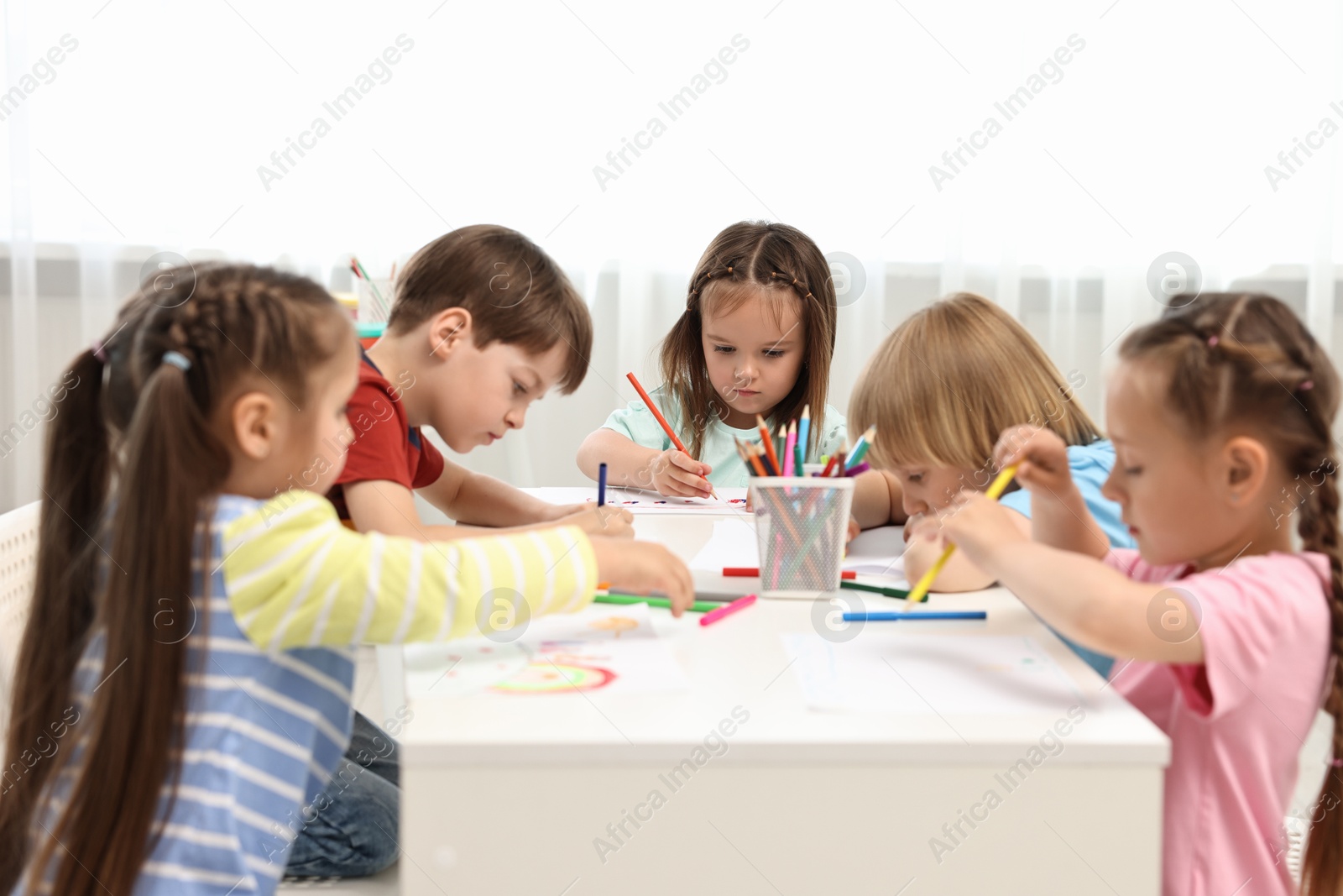 Photo of Group of children drawing at table indoors