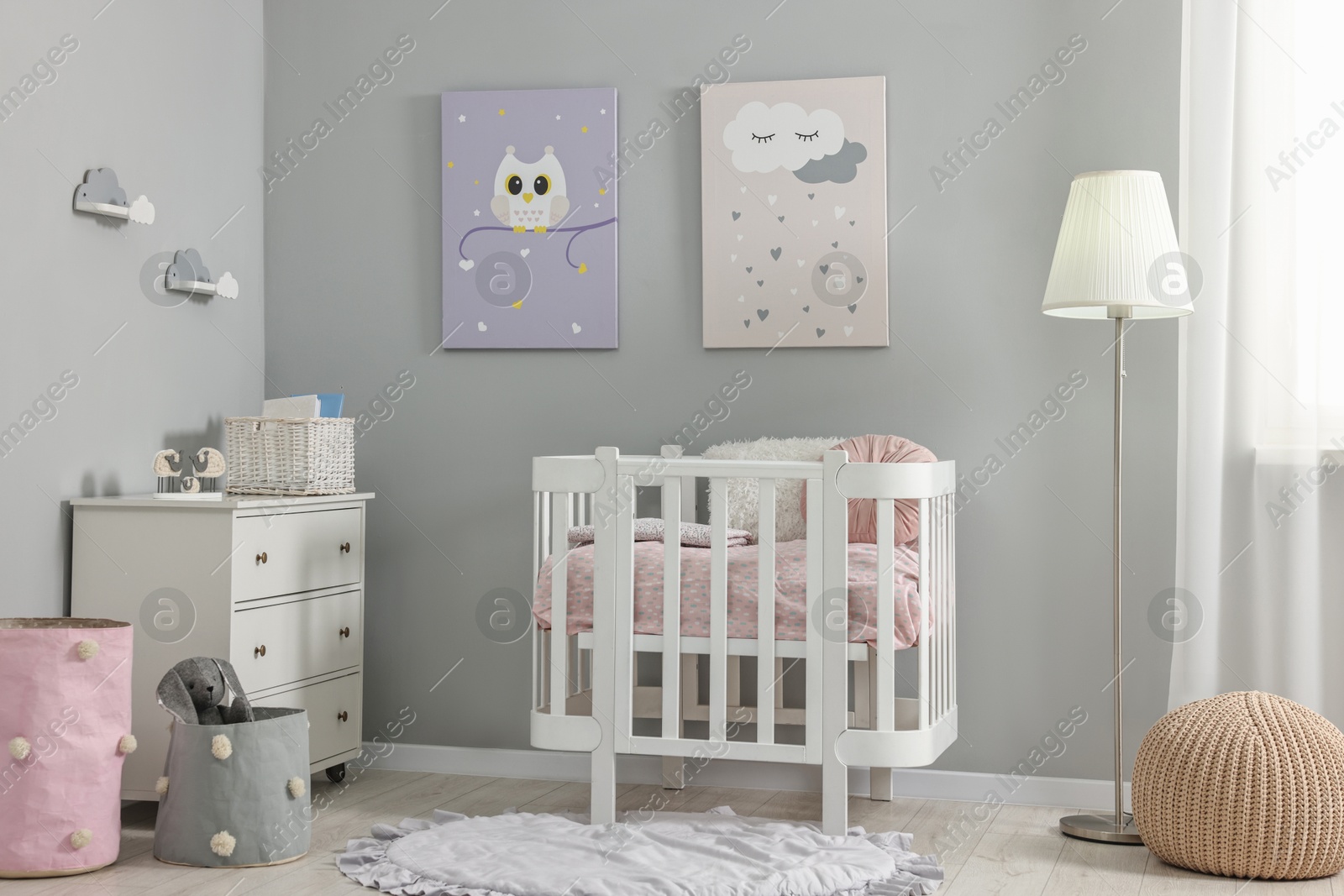 Photo of Newborn baby room interior with stylish furniture, comfortable crib and pictures of on wall