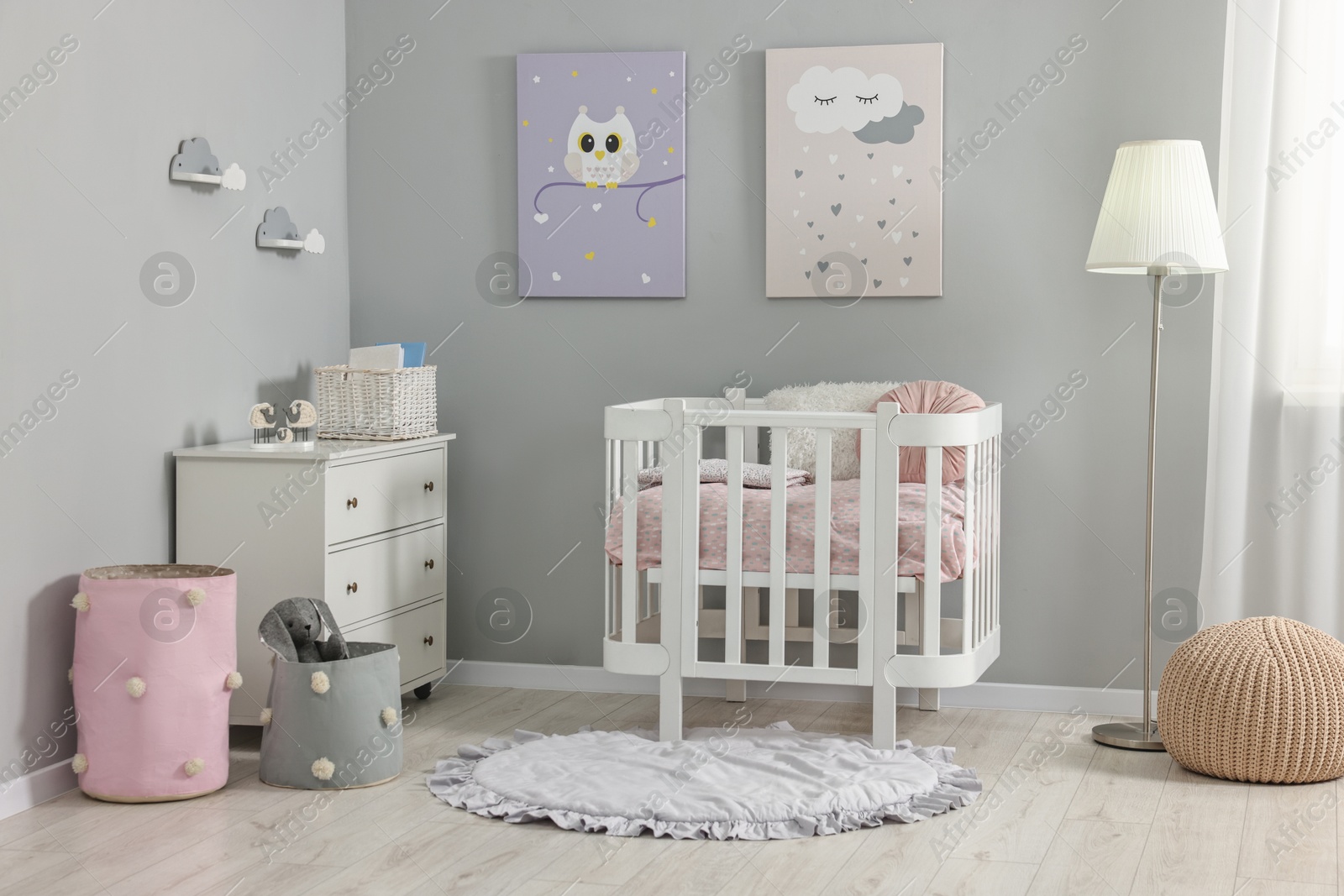 Photo of Newborn baby room interior with stylish furniture, comfortable crib and pictures of on wall