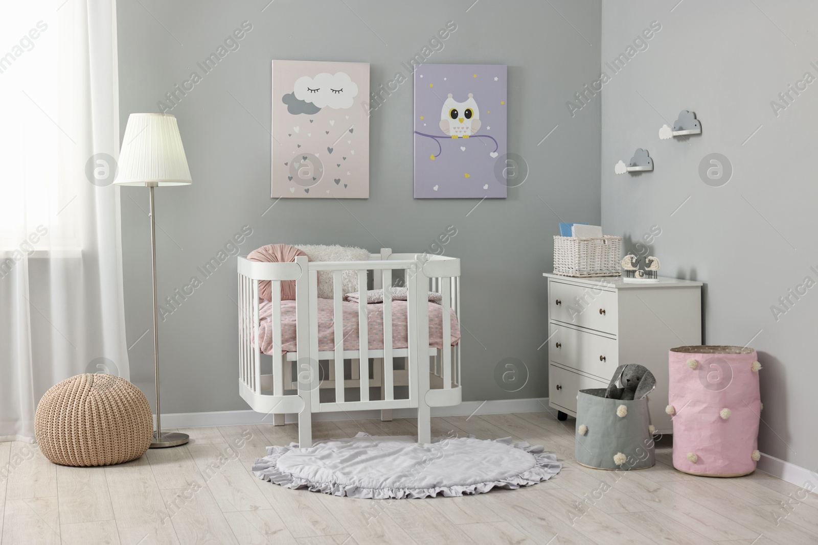 Photo of Newborn baby room interior with stylish furniture, comfortable crib and pictures of on wall