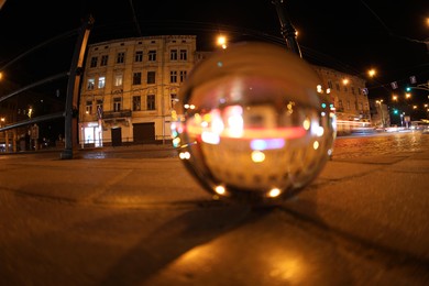 Photo of Crystal ball on asphalt road at night, selective focus. Wide-angle lens