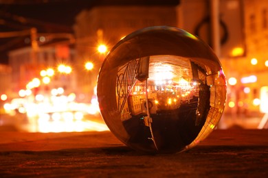 Photo of Beautiful city street, overturned reflection. Crystal ball at night, closeup. Space for text