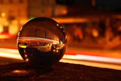 Beautiful city street, overturned reflection. Crystal ball at night, closeup. Space for text