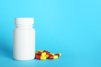 Photo of Antibiotic pills and bottle on light blue background, space for text. Medicinal treatment