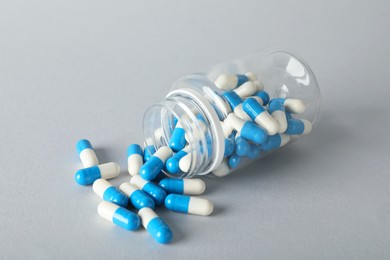 Photo of Scattered antibiotic pills and bottle on grey background. Medicinal treatment