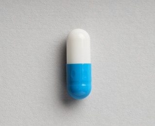 Photo of One antibiotic pill on grey background, top view. Medicinal treatment