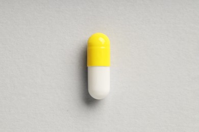 Photo of One antibiotic pill on grey background, top view. Medicinal treatment