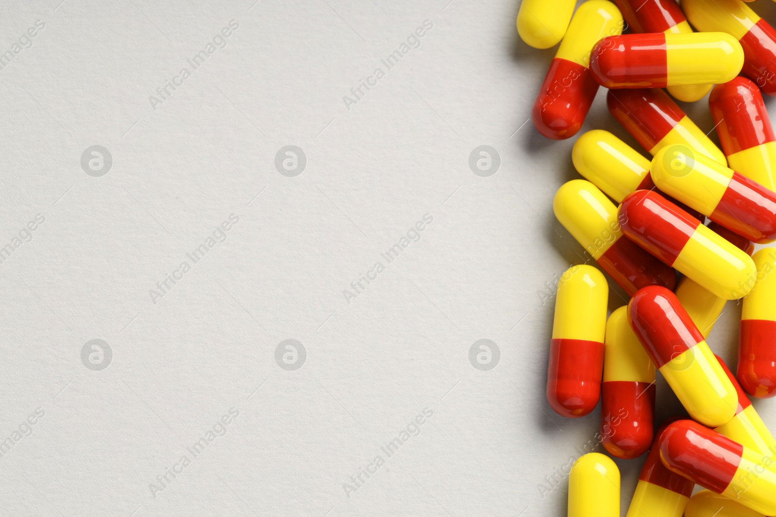 Photo of Many antibiotic pills on grey background, top view and space for text. Medicinal treatment