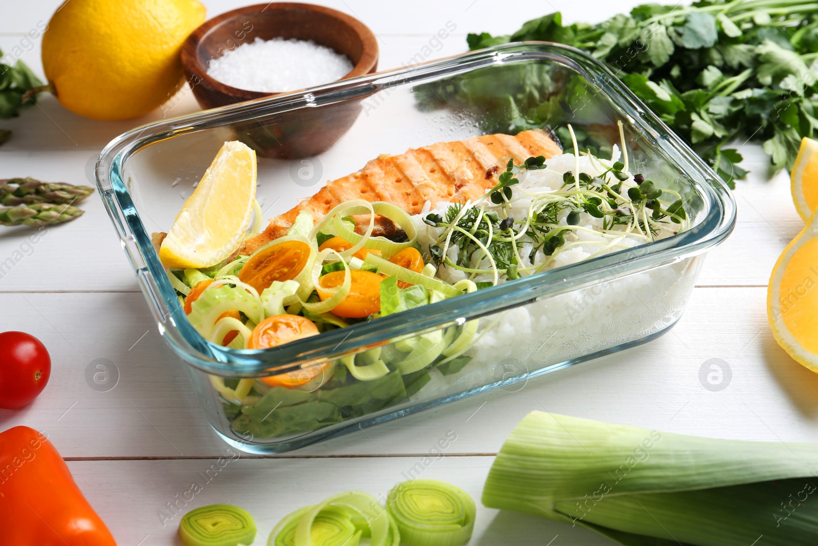 Photo of Healthy meal. Salmon, rice and salad in container near other products on white wooden table