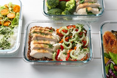 Photo of Healthy meal. Containers with different products on white wooden table