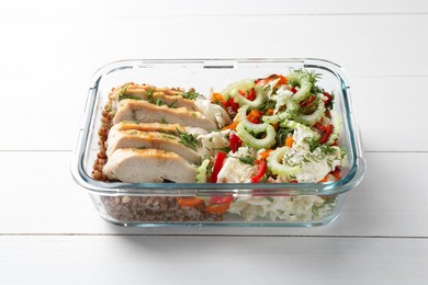 Photo of Healthy meal. Chicken breast, buckwheat and salad in container on white wooden table