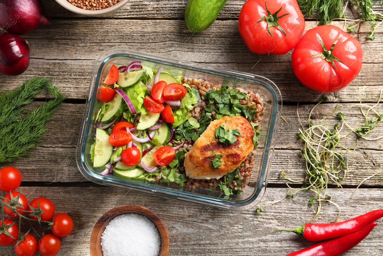 Photo of Healthy meal. Cutlet, buckwheat and salad in container near other products on wooden table, flat lay