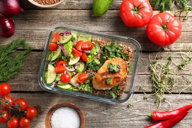 Photo of Healthy meal. Cutlet, buckwheat and salad in container near other products on wooden table, flat lay