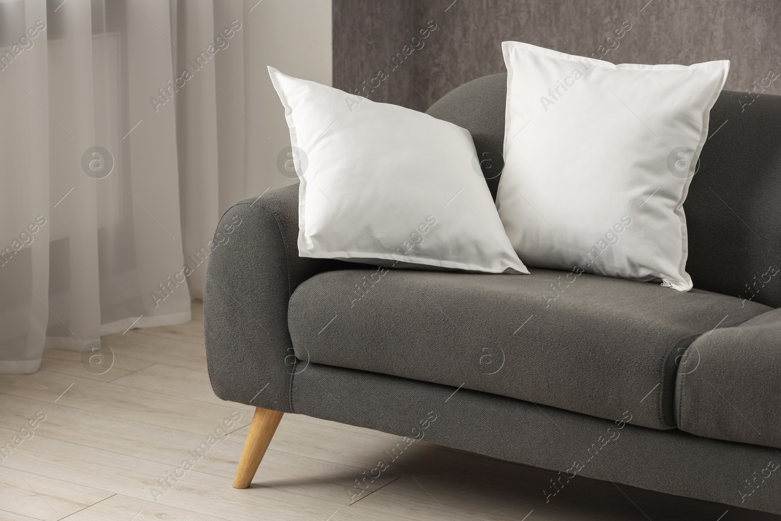 Photo of Two soft white pillows on sofa indoors