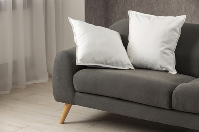 Photo of Two soft white pillows on sofa indoors