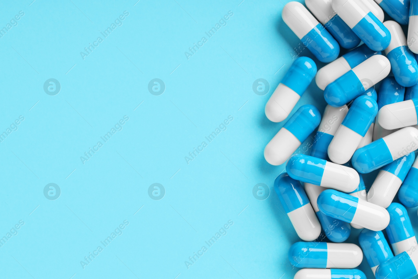 Photo of Many antibiotic pills and space for text on light blue background, top view. Medicinal treatment