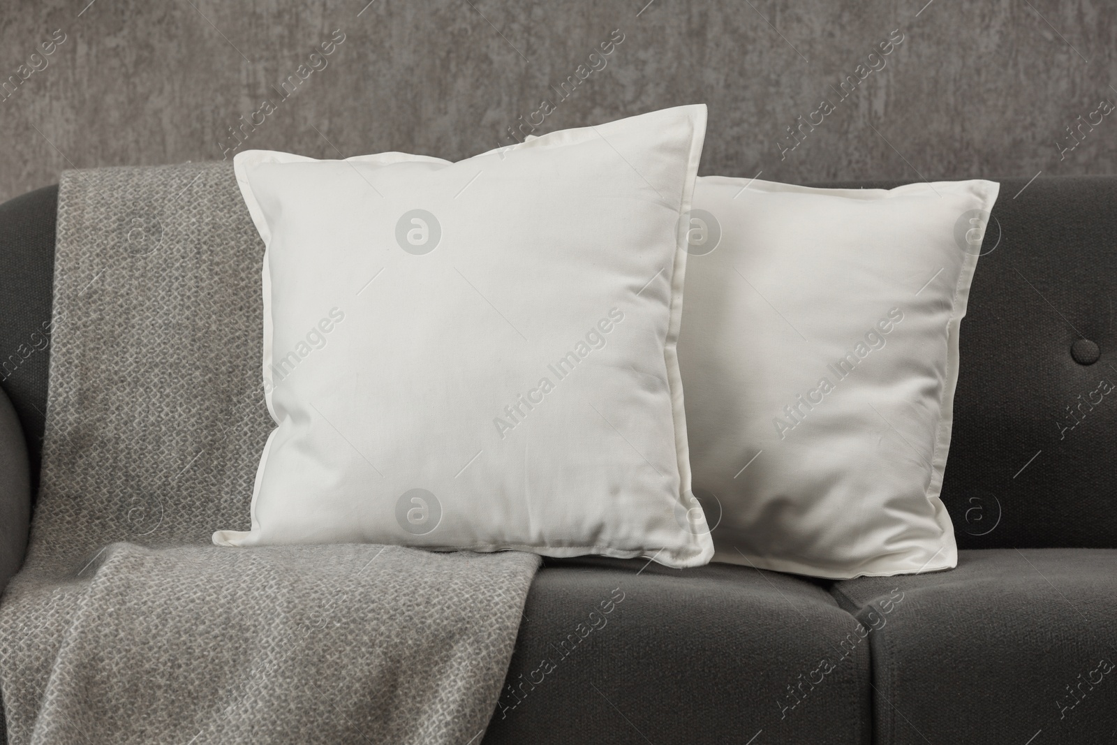 Photo of Soft white pillows and blanket on sofa indoors