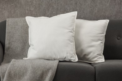 Soft white pillows and blanket on sofa indoors