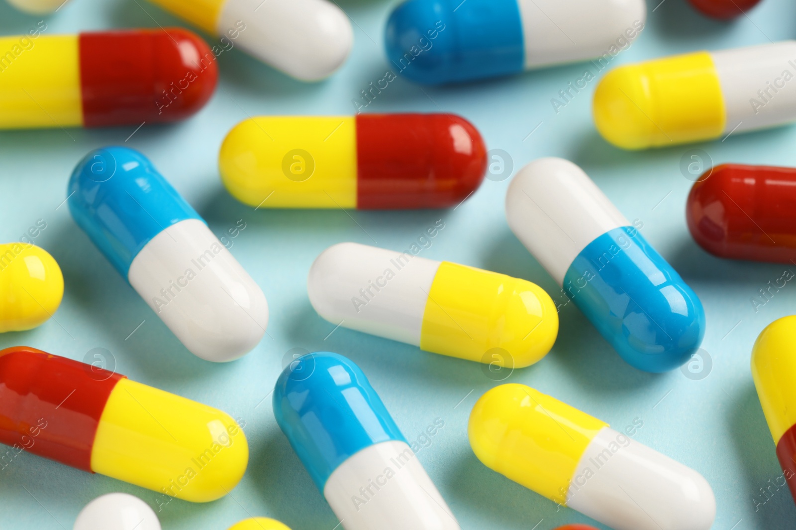 Photo of Many antibiotic pills on light blue background, closeup