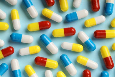 Photo of Many antibiotic pills on light blue background, top view