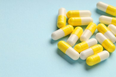 Photo of Many antibiotic pills on light blue background, closeup. Space for text