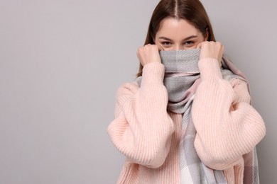 Photo of Beautiful woman in warm scarf on gray background, space for text