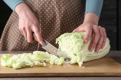 Healthy food. Woman cutting Chinese cabbage at grey table, closeup