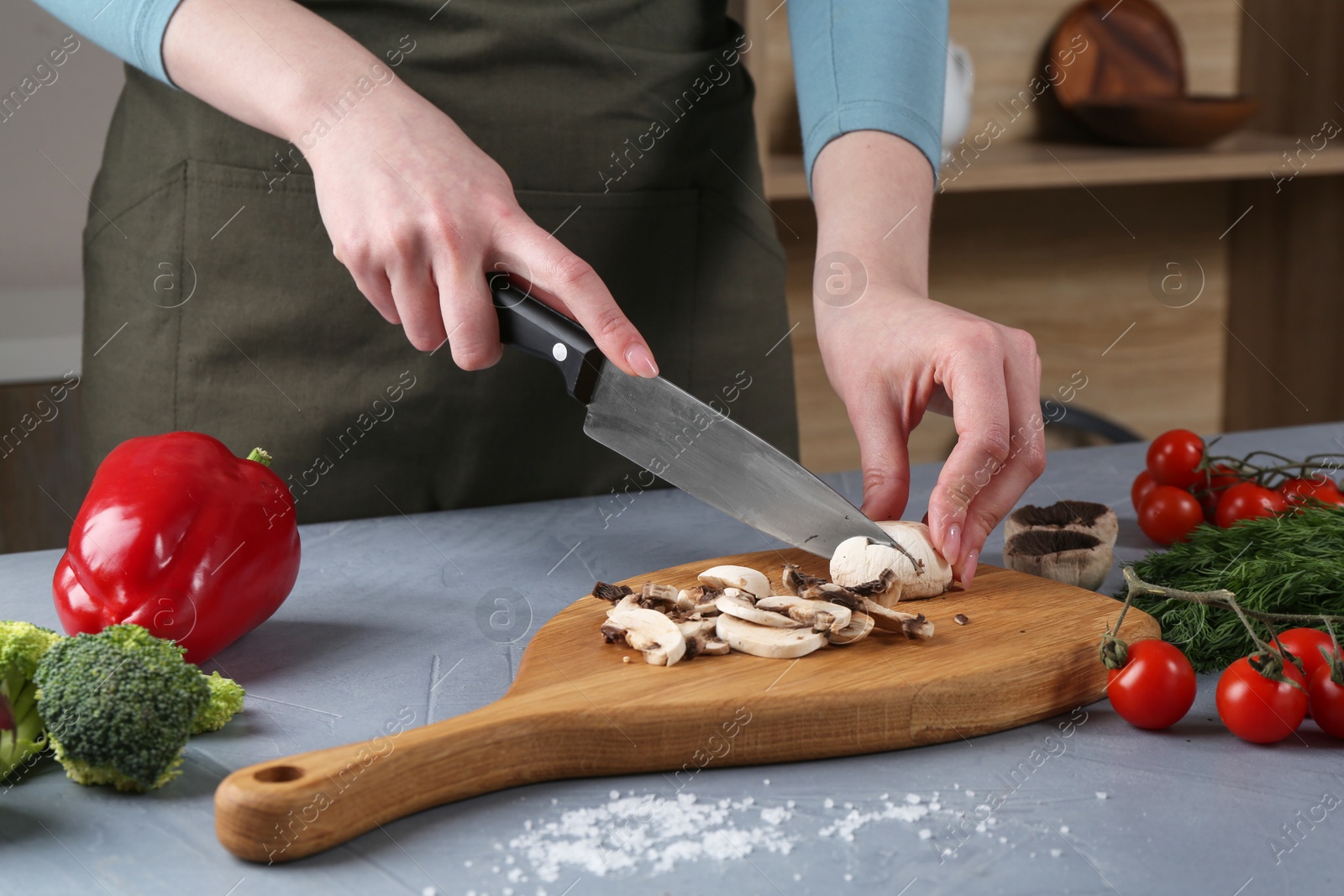 Photo of Healthy food. Woman cutting champignon at grey table, closeup