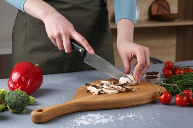 Healthy food. Woman cutting champignon at grey table, closeup