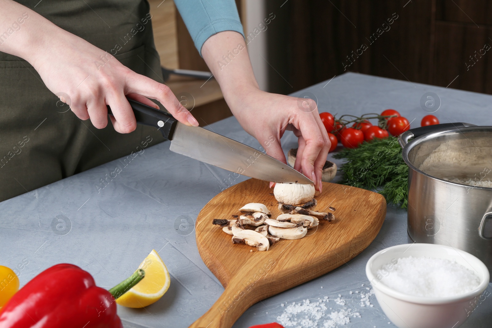 Photo of Healthy food. Woman cutting champignon at grey table, closeup