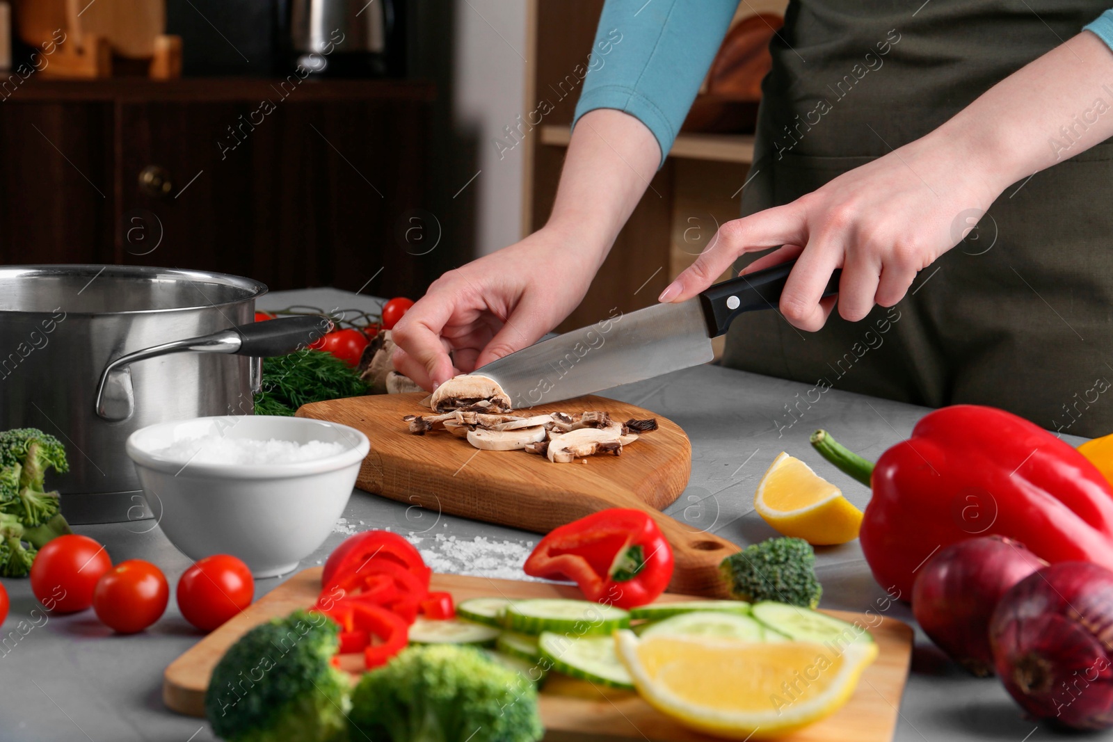 Photo of Healthy food. Woman cutting champignon at grey table, closeup