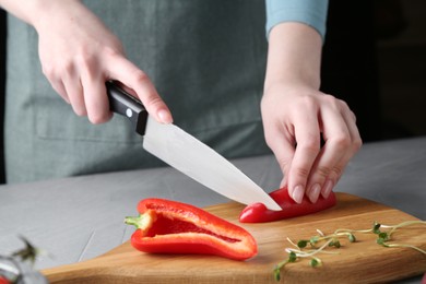 Healthy food. Woman cutting pepper at grey table, closeup