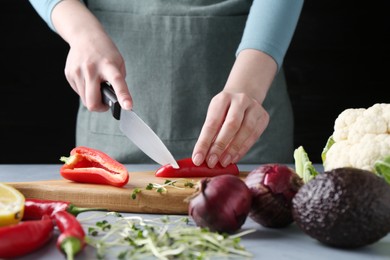 Photo of Healthy food. Woman cutting pepper at grey table, closeup