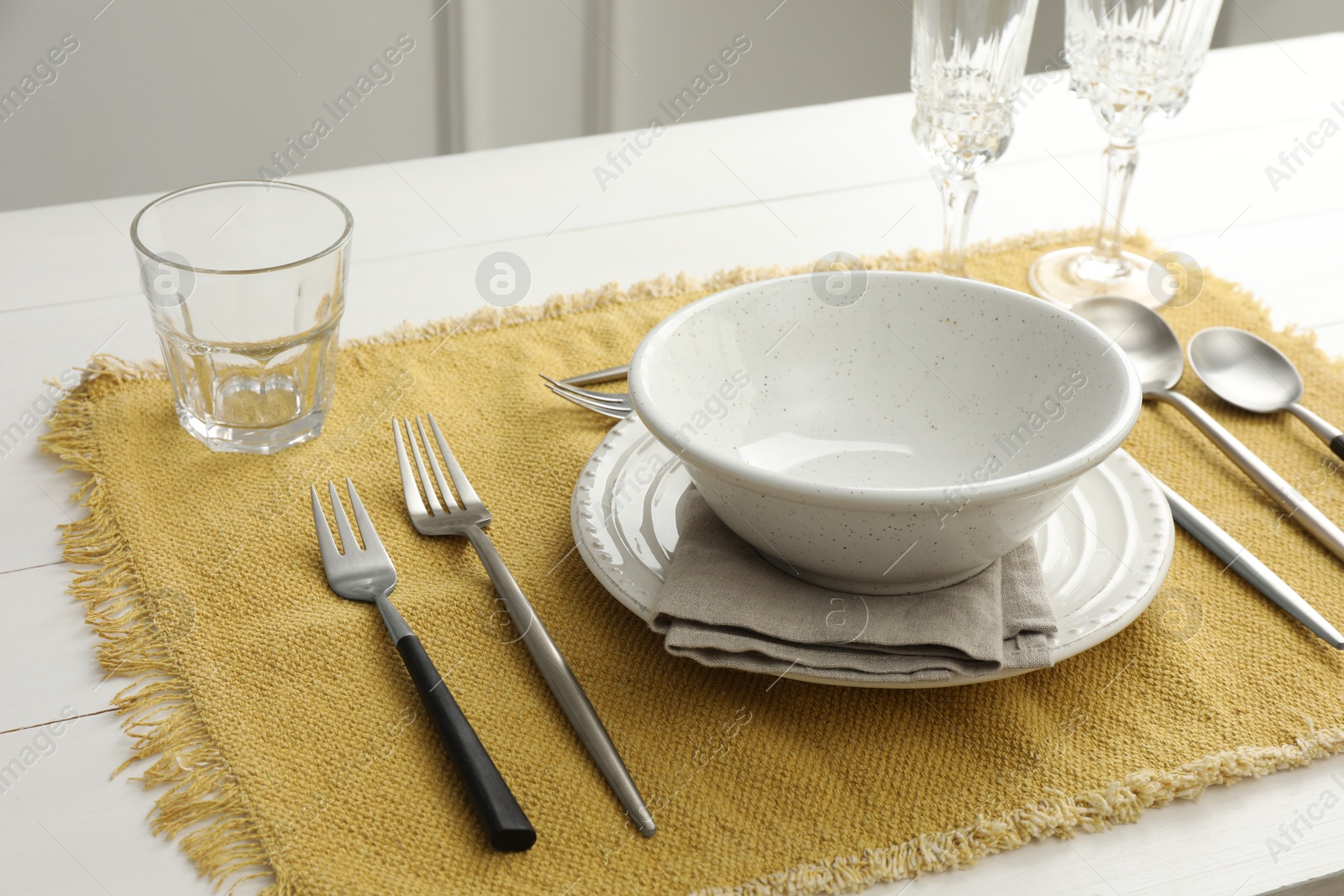 Photo of Stylish setting with cutlery, dishes, glasses and napkin on white wooden table