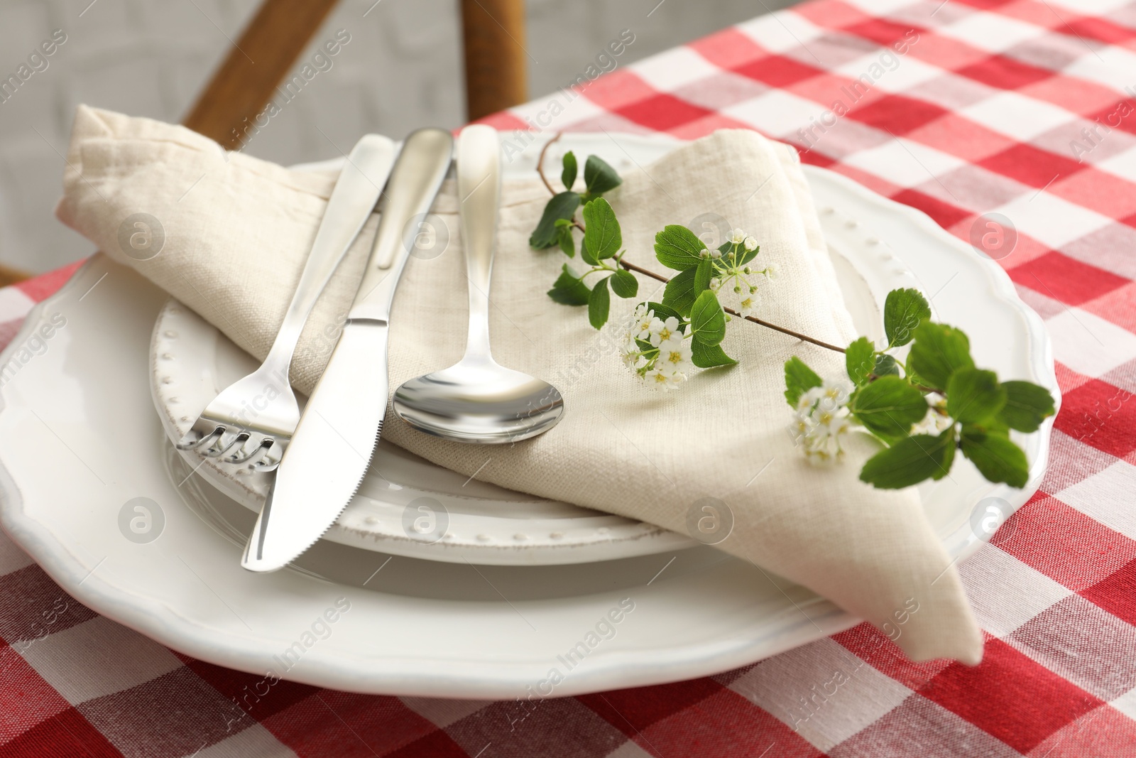 Photo of Stylish setting with cutlery, plates, napkin and floral decor on table, closeup