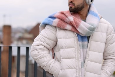 Man in warm scarf and headphones outdoors, closeup