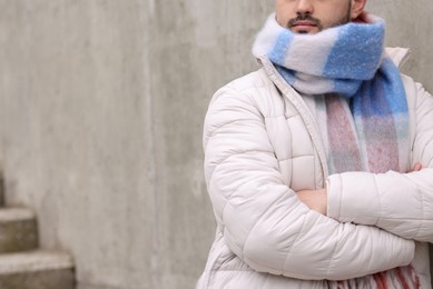 Man in warm scarf near wall outdoors, closeup. Space for text