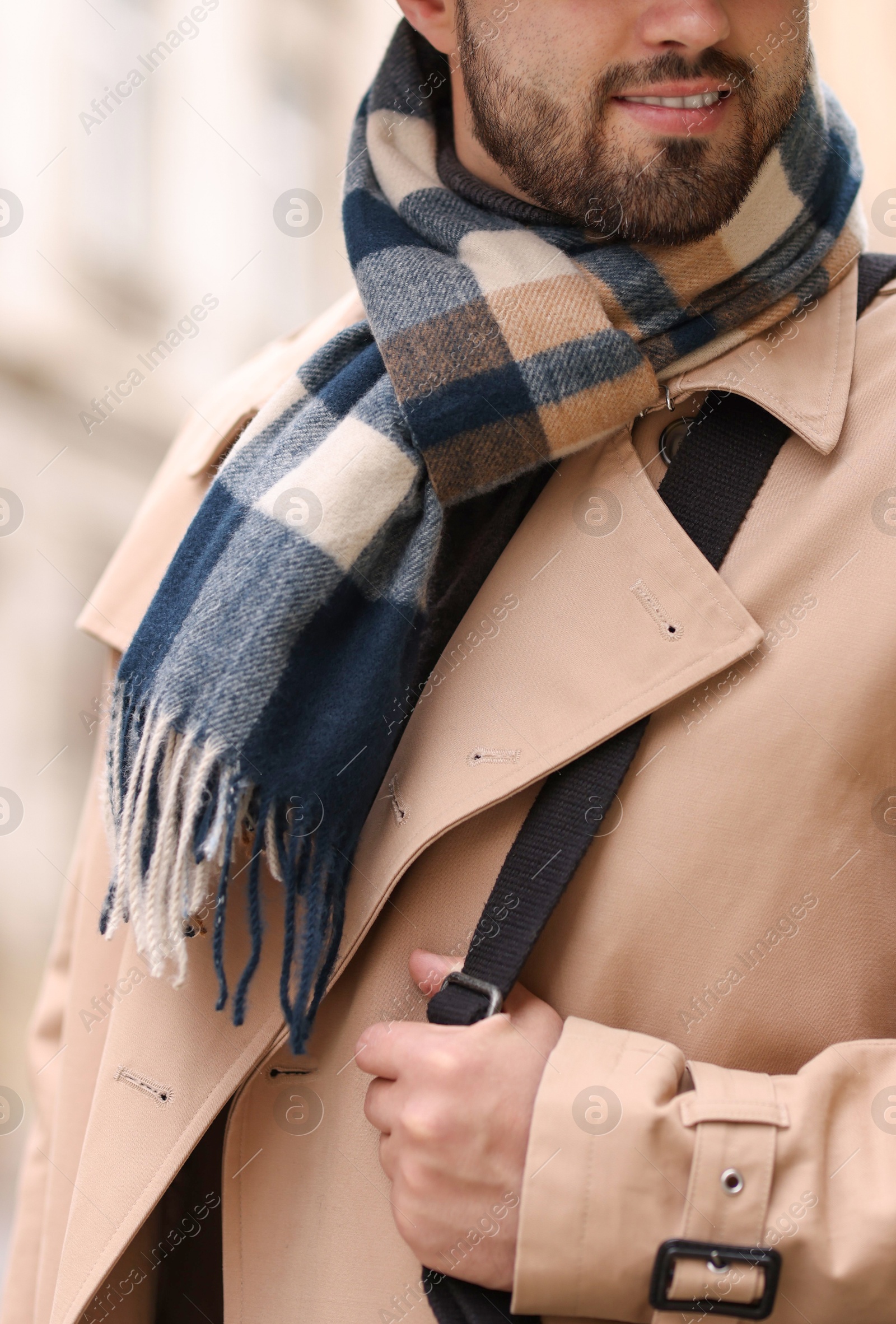 Photo of Smiling man in warm scarf on blurred background, closeup